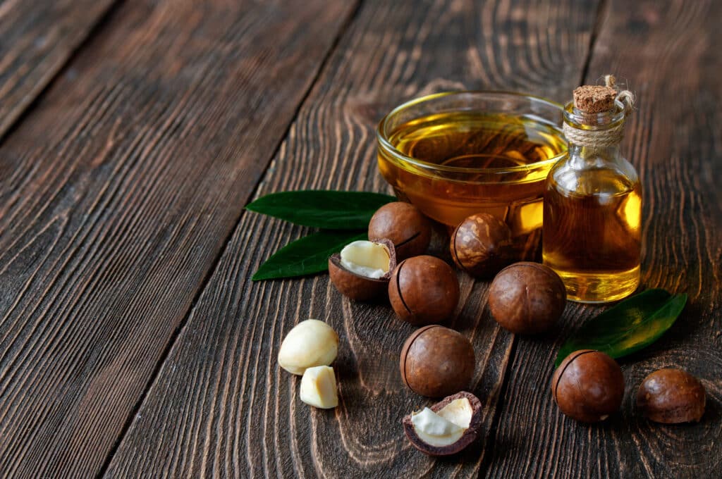 Organic macadamia oil and macadamia nuts on a wooden background.